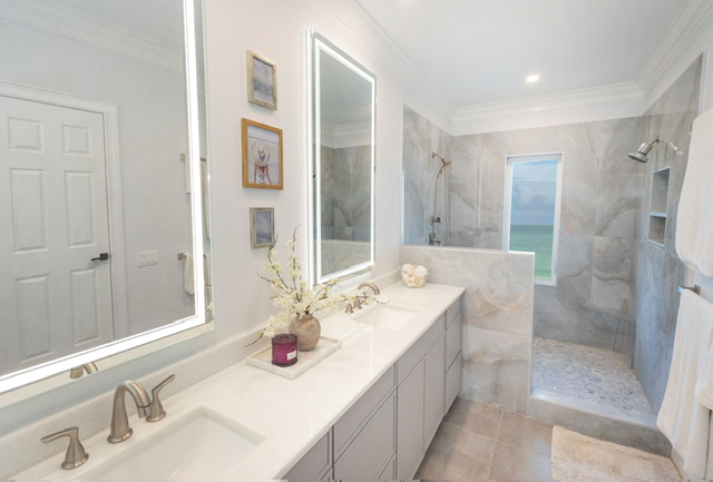Bathroom with double vanity, large mirror, decorative items, and a walk-in shower with window.