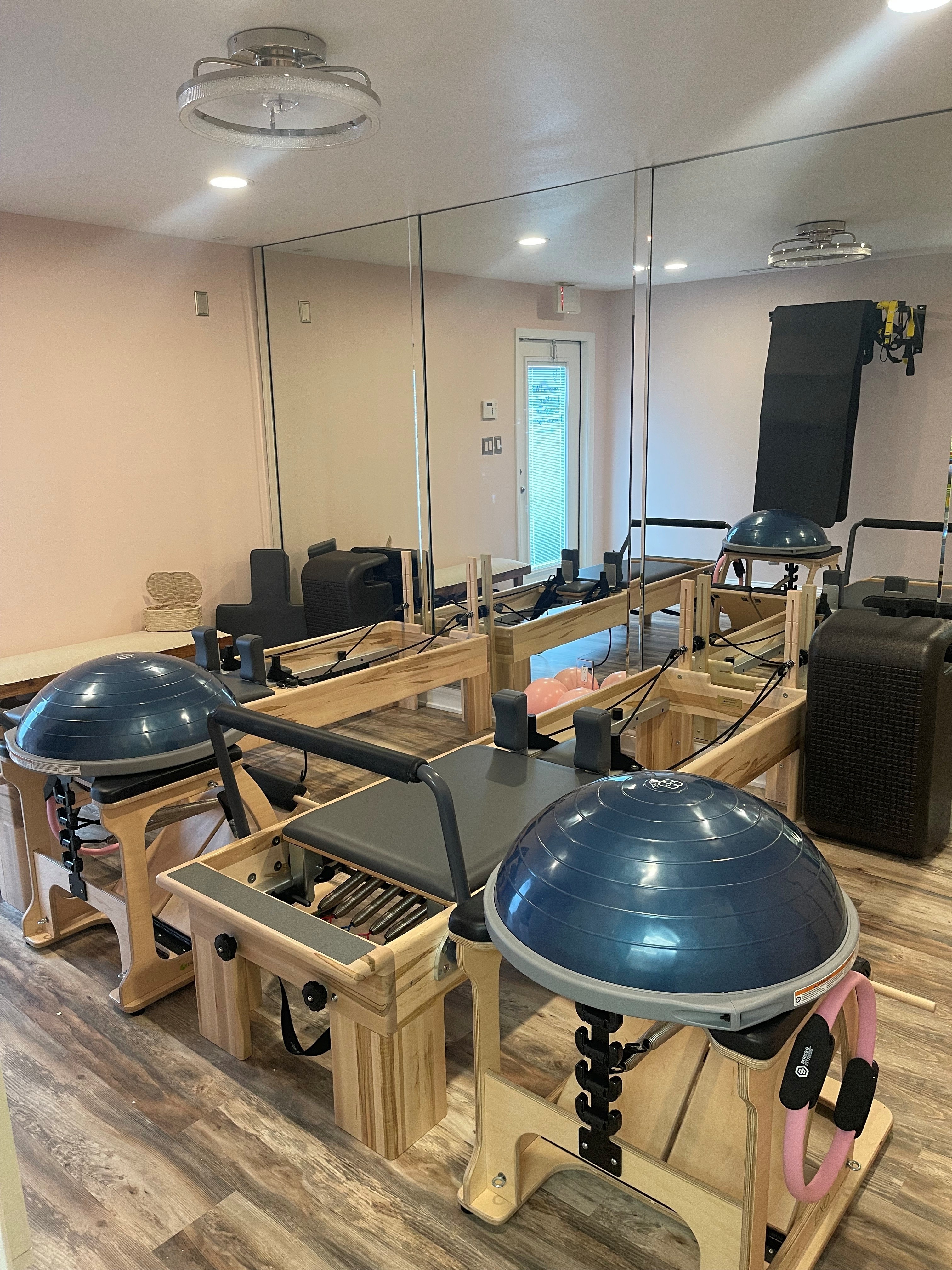 Gym equipment including balance balls, a mirror wall, and workout machines in a fitness room.