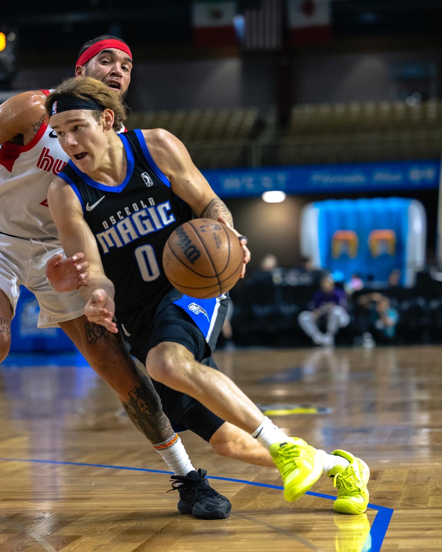 Basketball player dribbling the ball while being guarded by an opponent on the court.