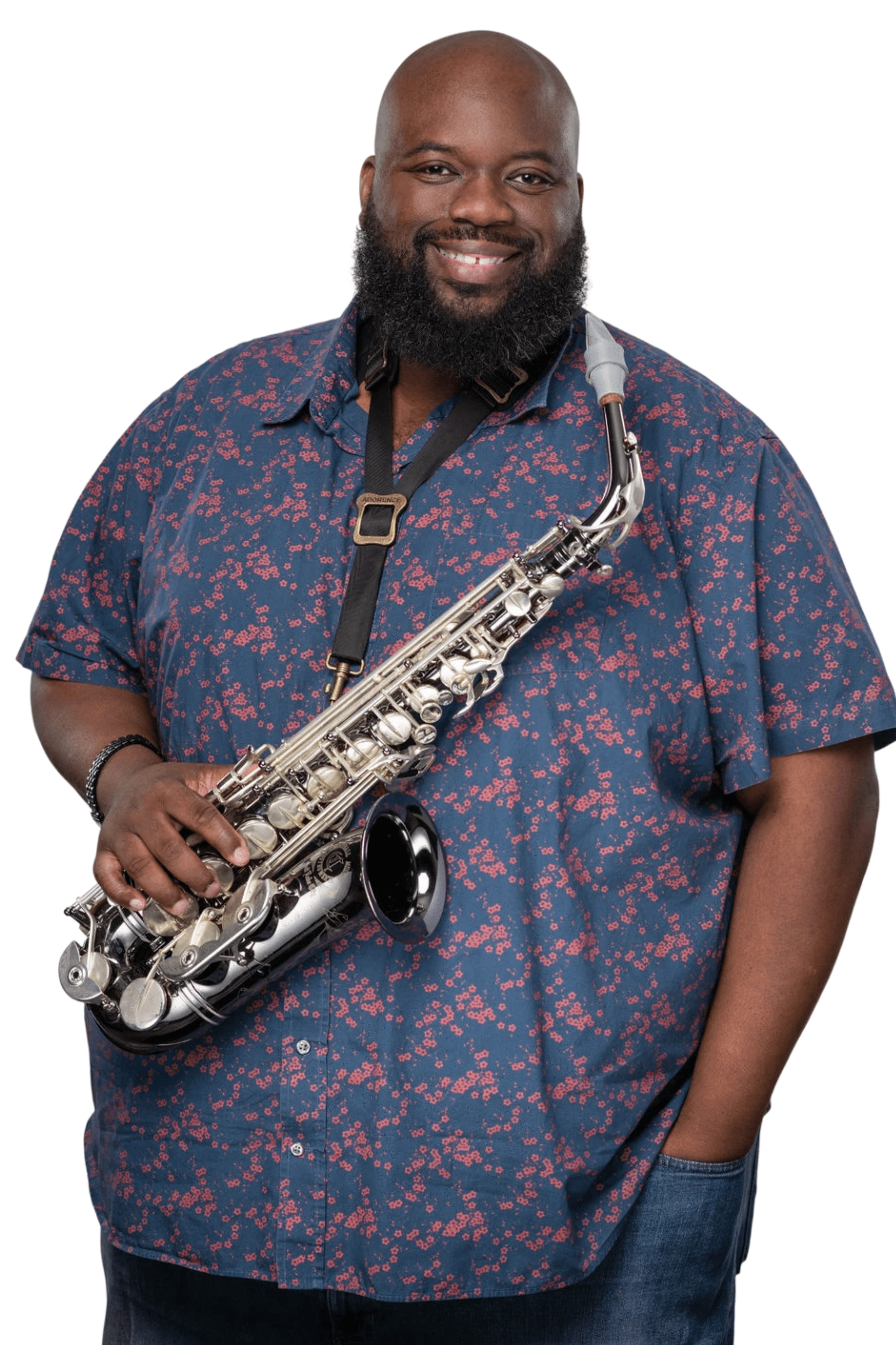 Man with a beard holding a saxophone, smiling, wearing a blue patterned shirt, standing against a white background.
