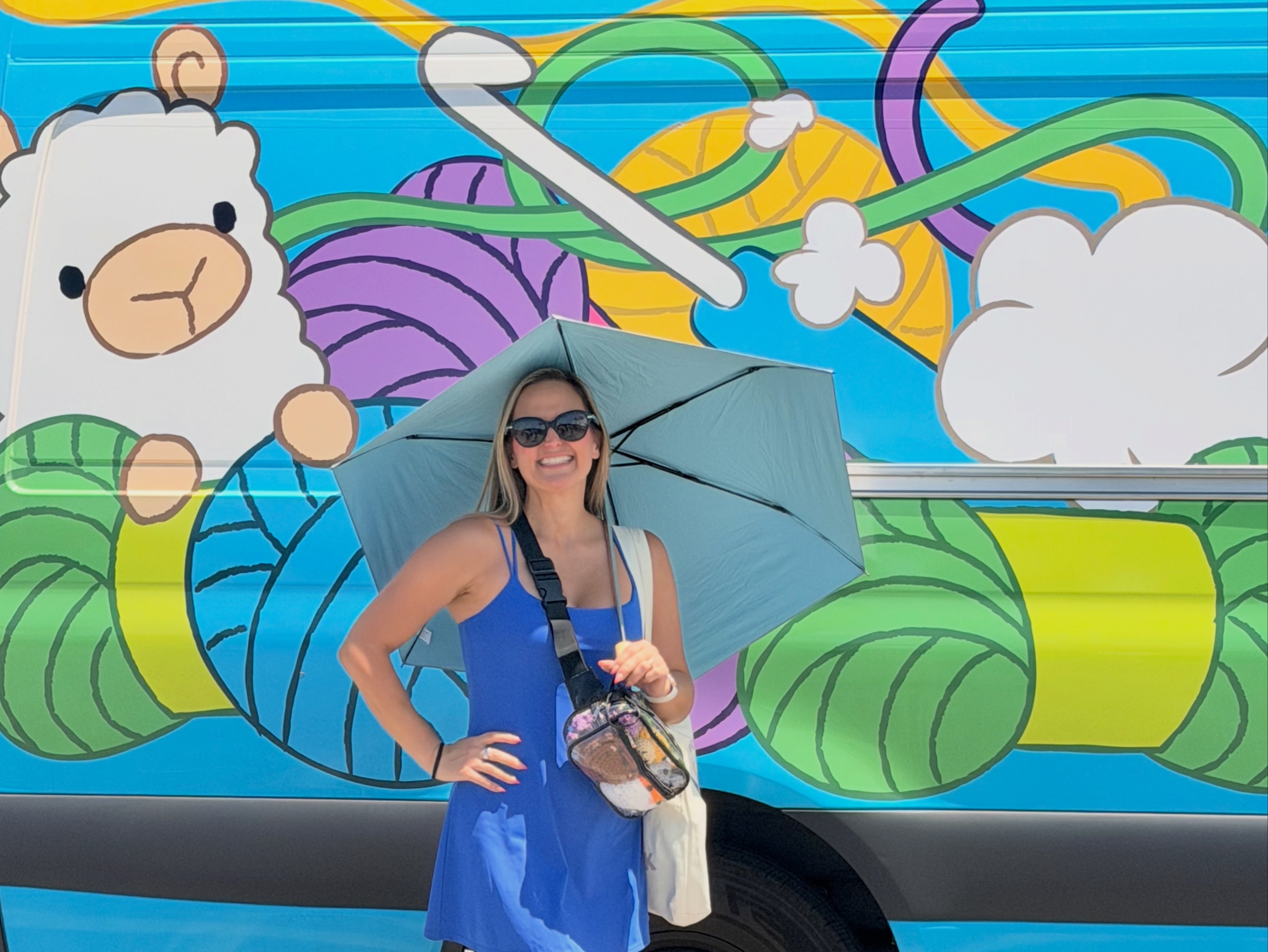 Woman with sunglasses holding an umbrella in front of a colorful mural with a bear and abstract shapes.