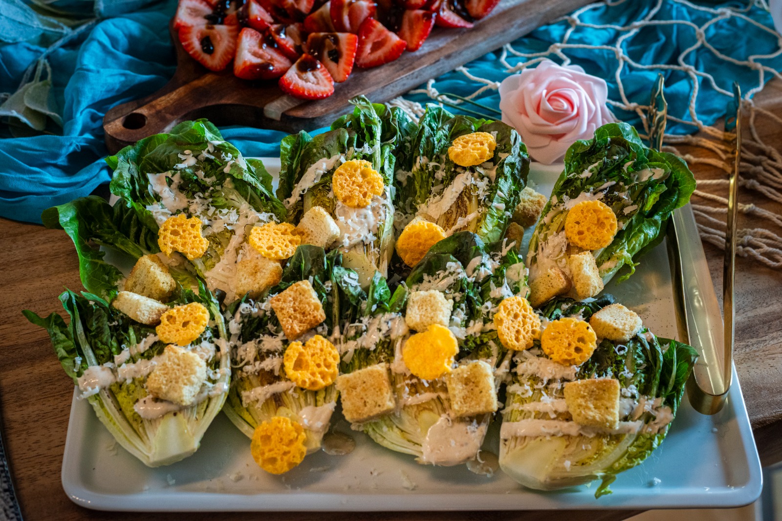 Tray of finger sandwiches with lettuce, yellow flowers, and bread, garnished with small yellow flowers, on a white platter.