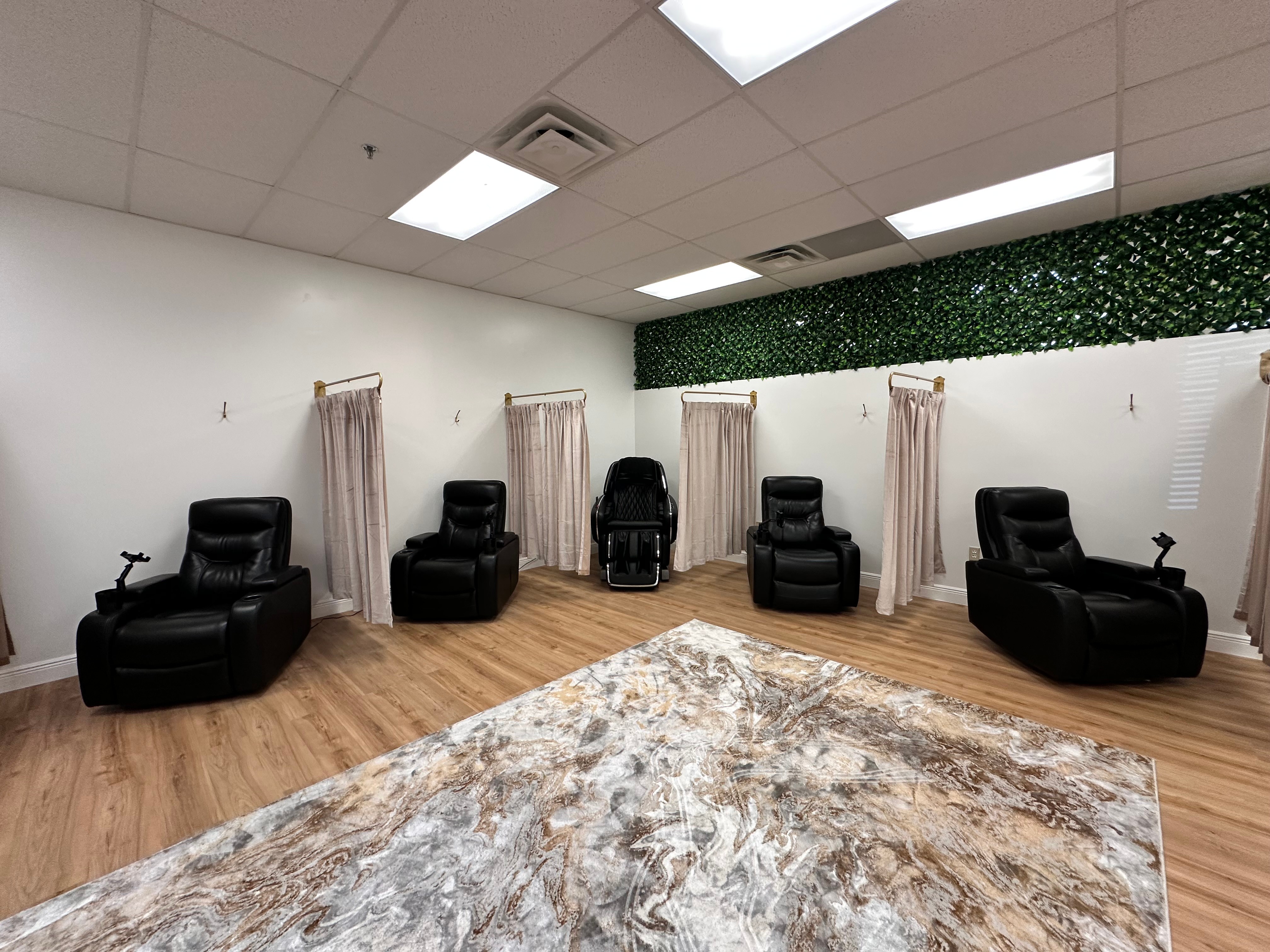 Room with five black chairs, curtains, and a green wall, with a marble-patterned floor and ceiling lights.