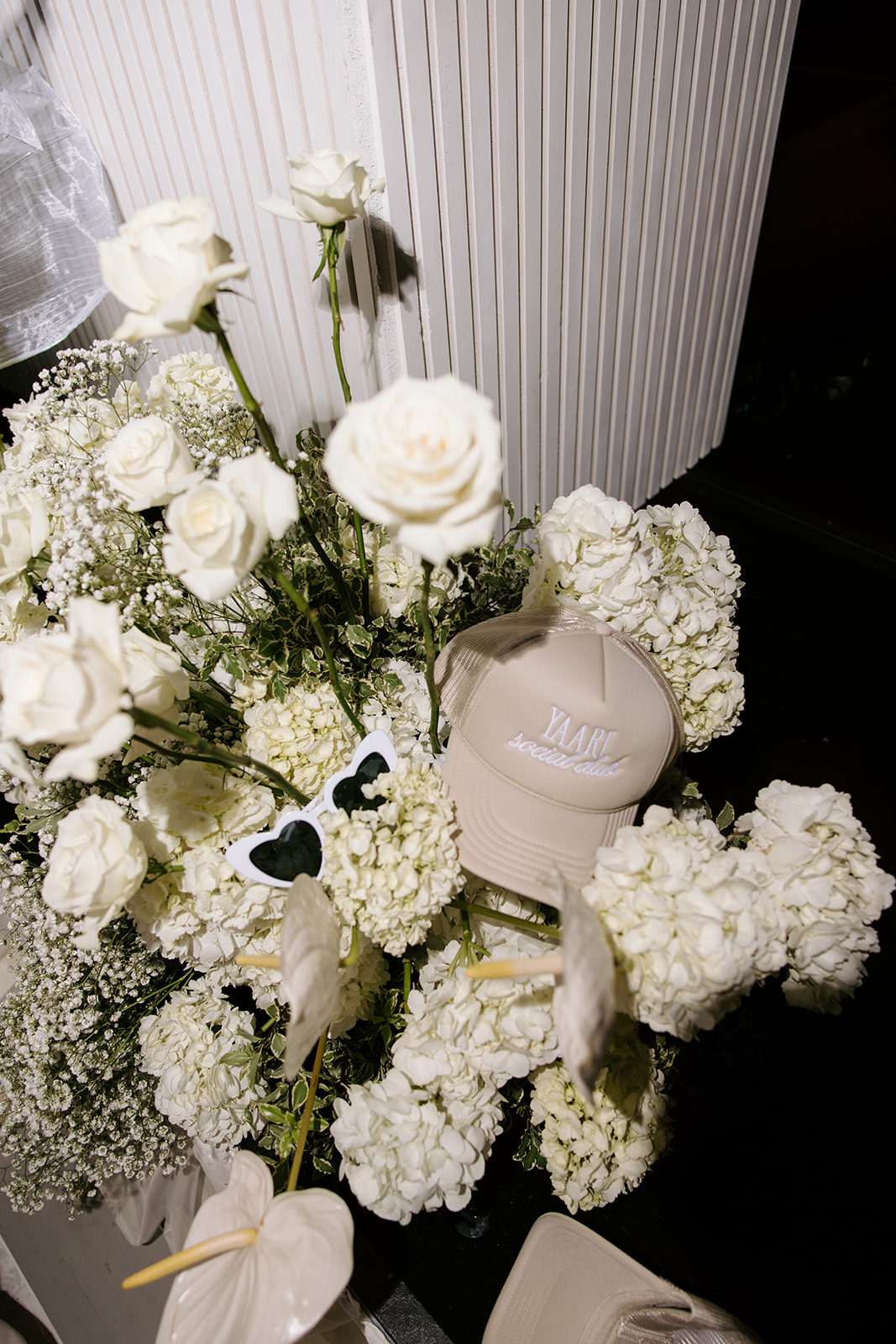 White flowers and a jewelry box on a dark surface, with a white textured background behind them.