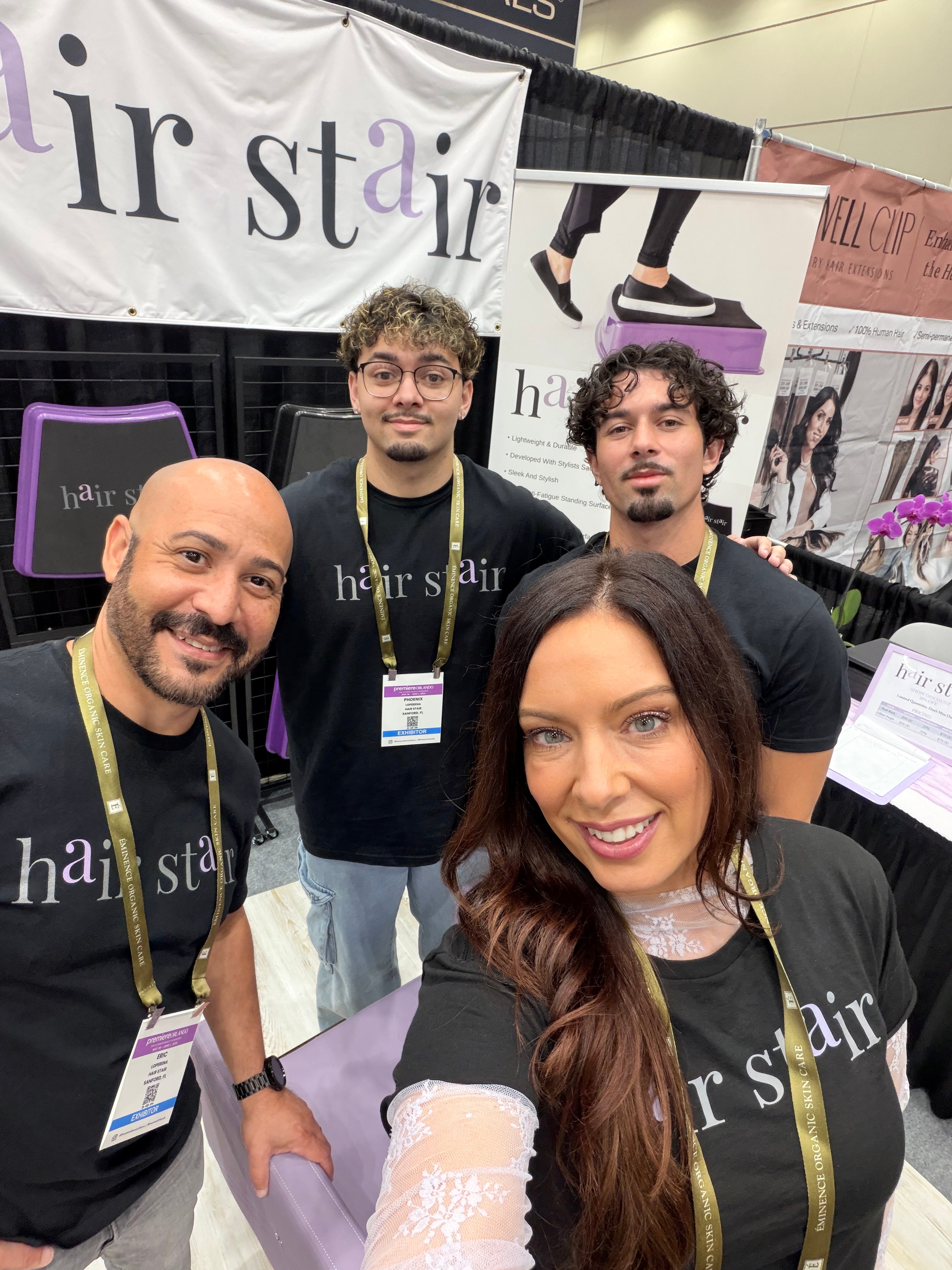 Four people smiling at a hair salon booth, with a banner reading 'hair star' behind them.