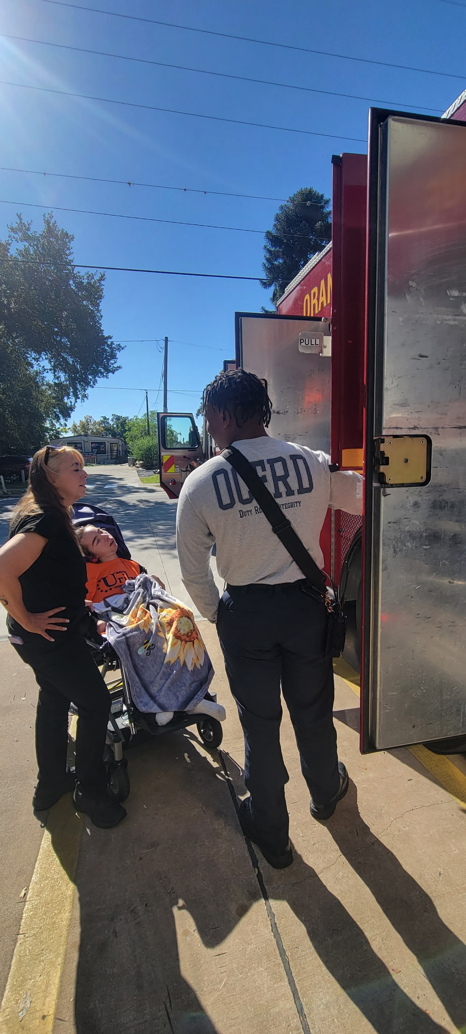 Two people standing outside a fast-food restaurant, one with a stroller, on a sunny day.