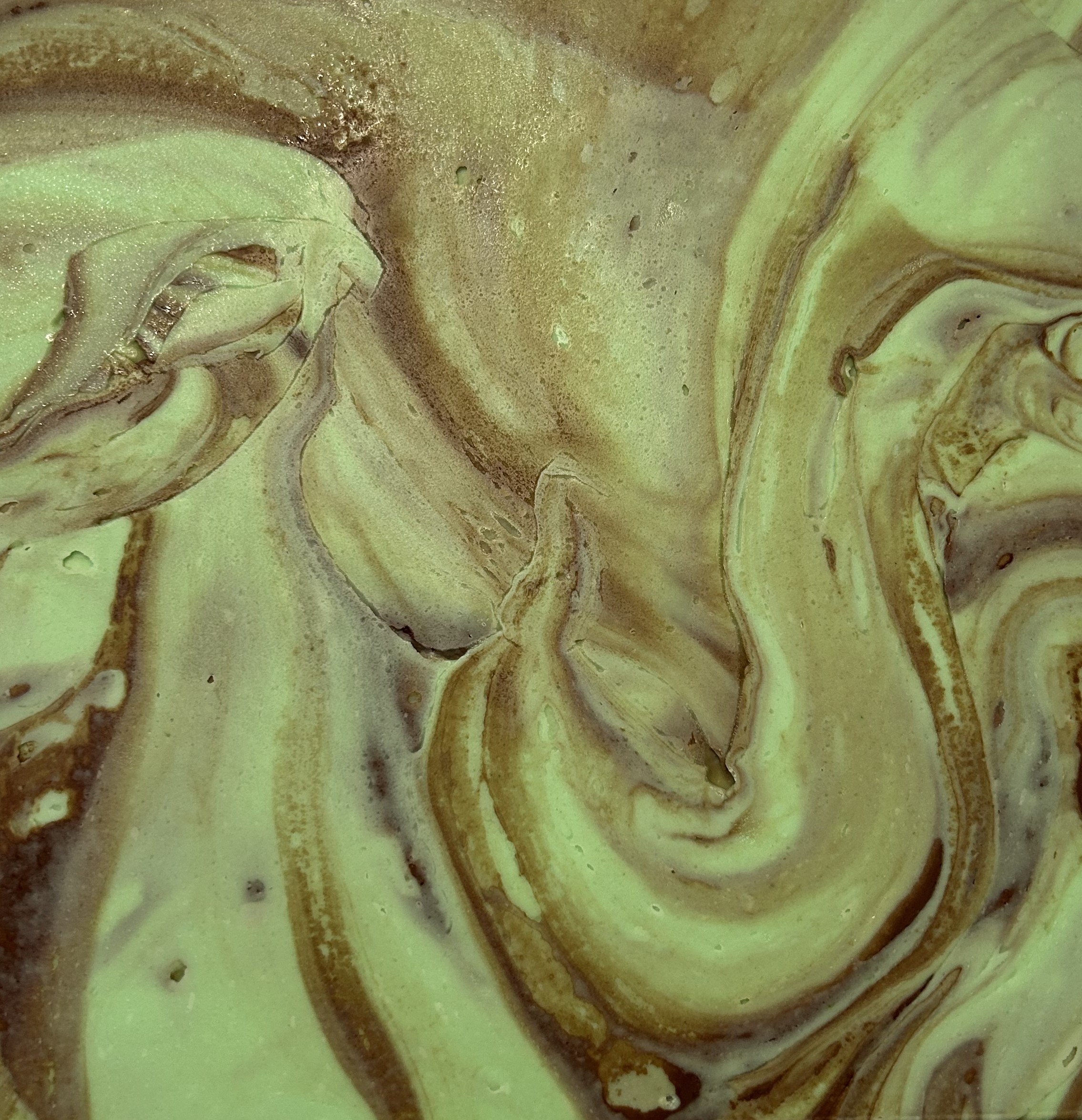 Swirling green and beige abstract pattern with fluid, marbled textures.