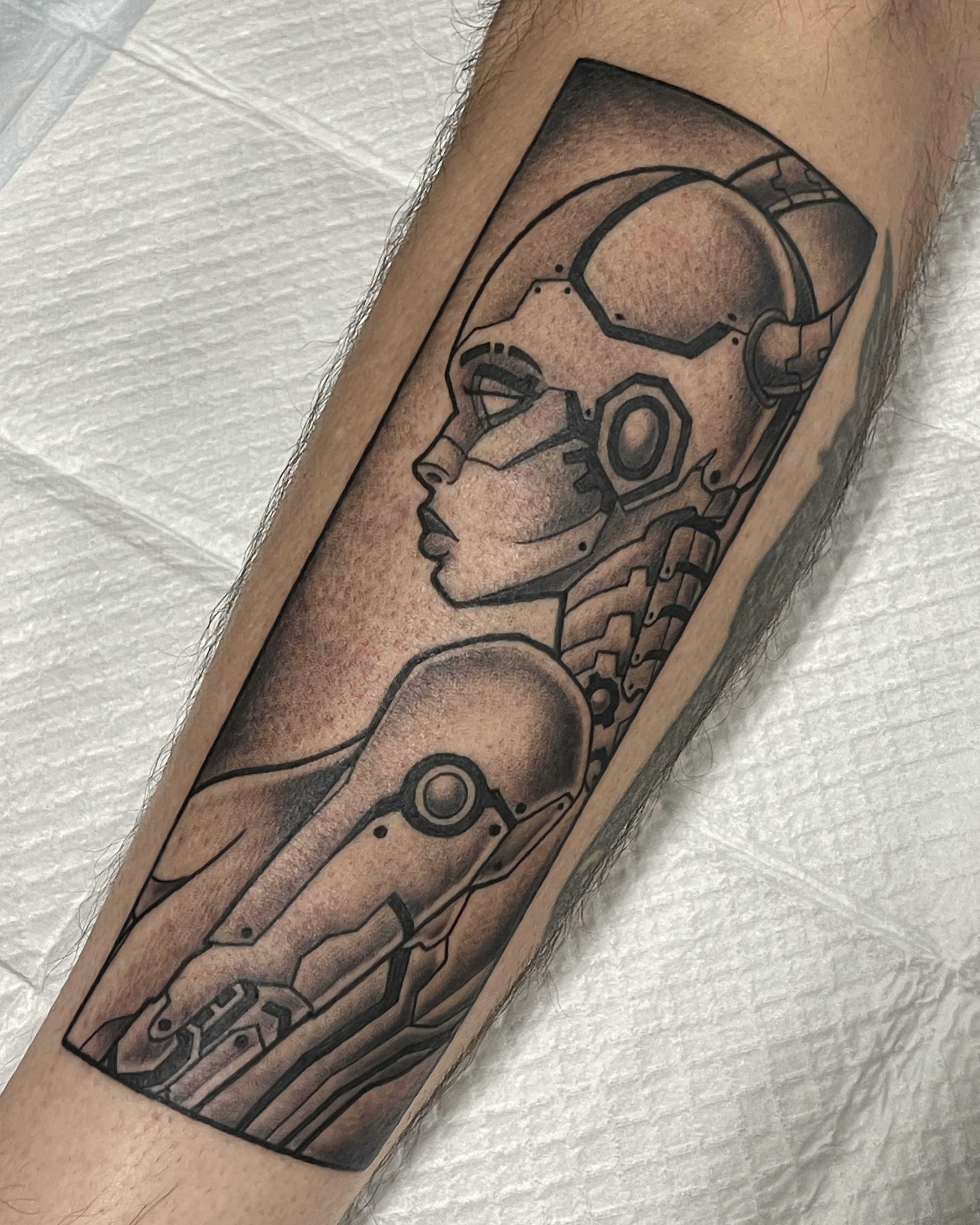 Black and gray tattoo of a woman's profile with futuristic robotic elements on arm.