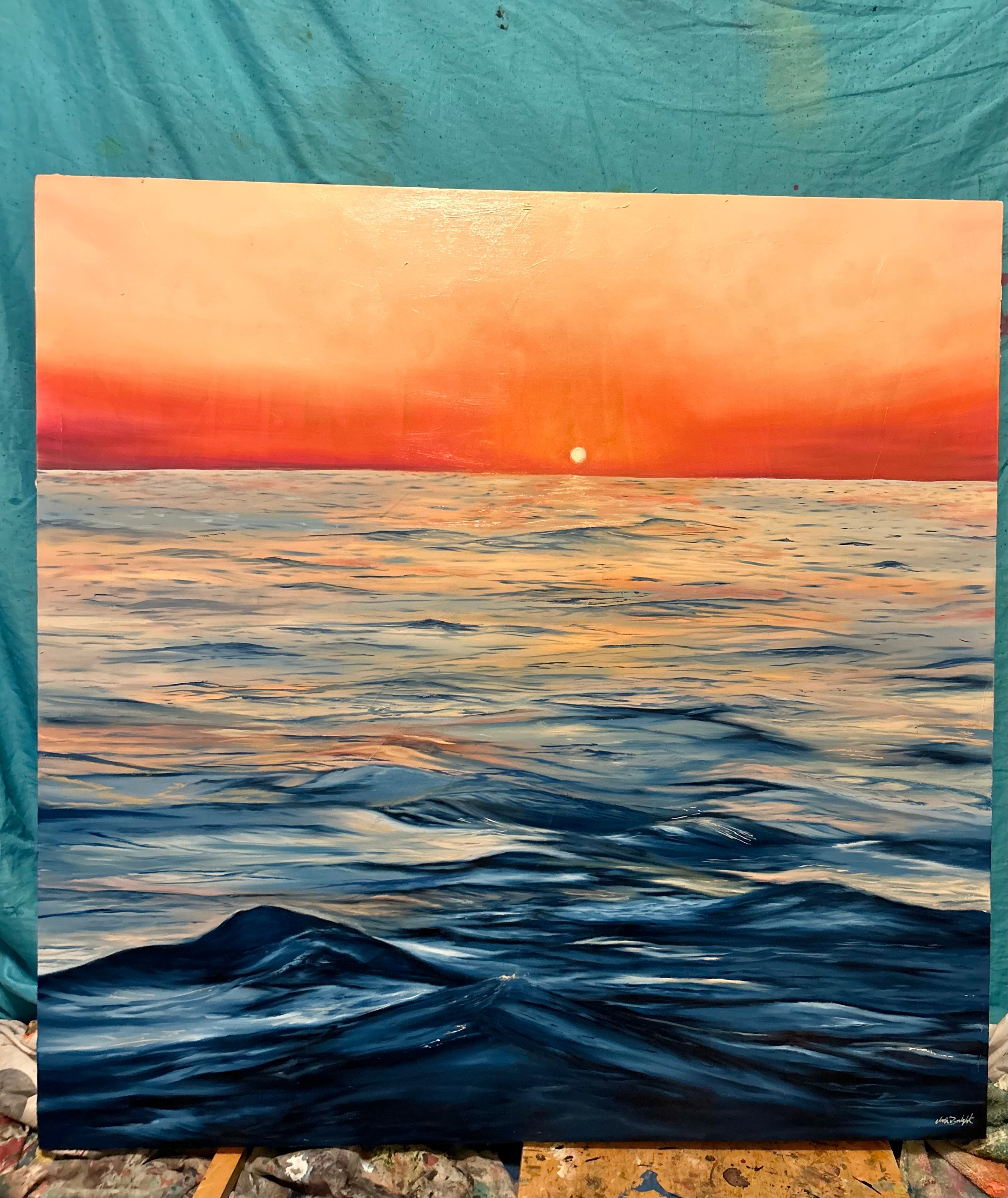 Sunset over the ocean with orange sky and calm blue water, horizon line visible.