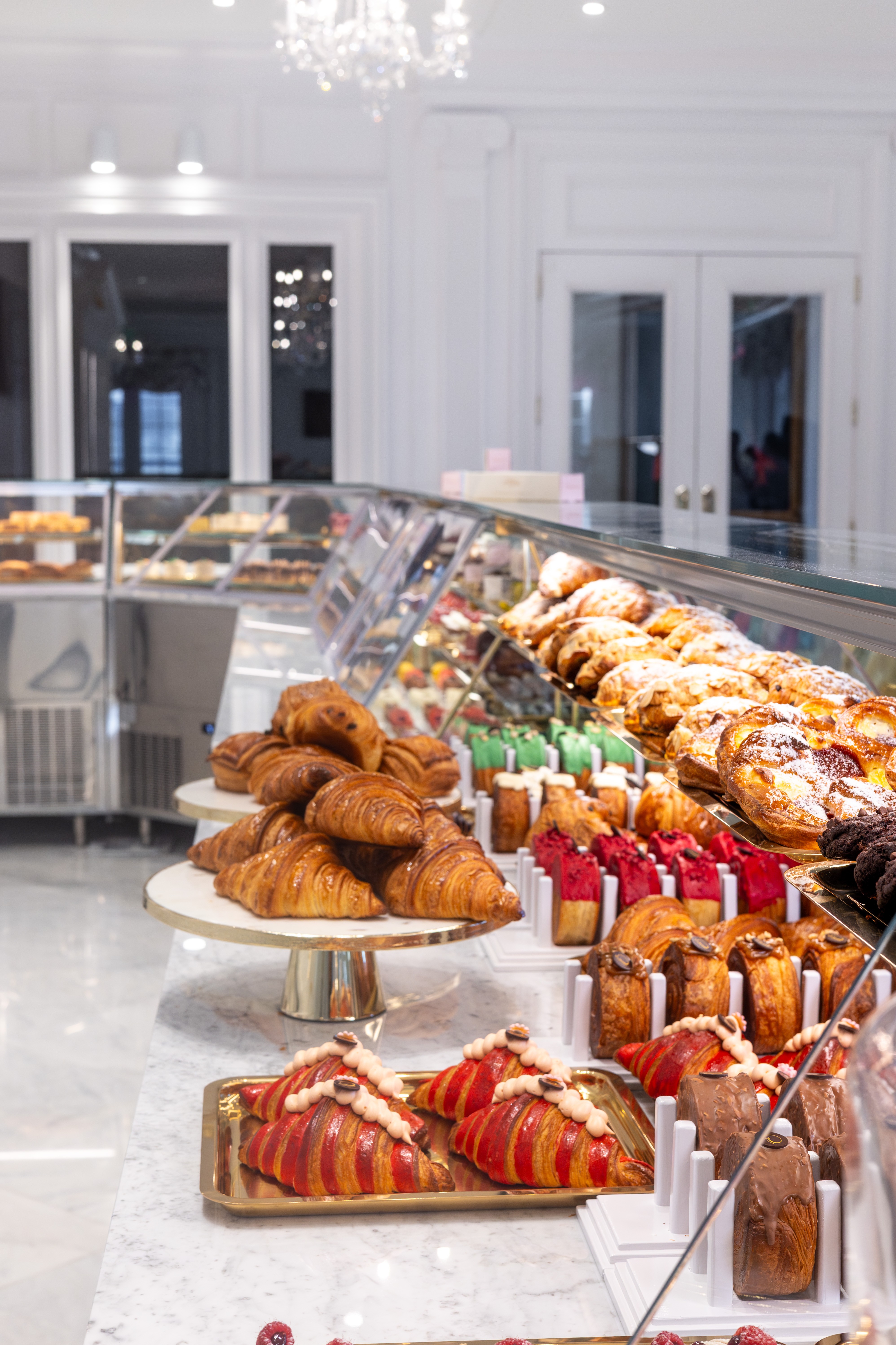 Display case with assorted pastries including croissants, cakes, and tarts in a bright bakery interior.