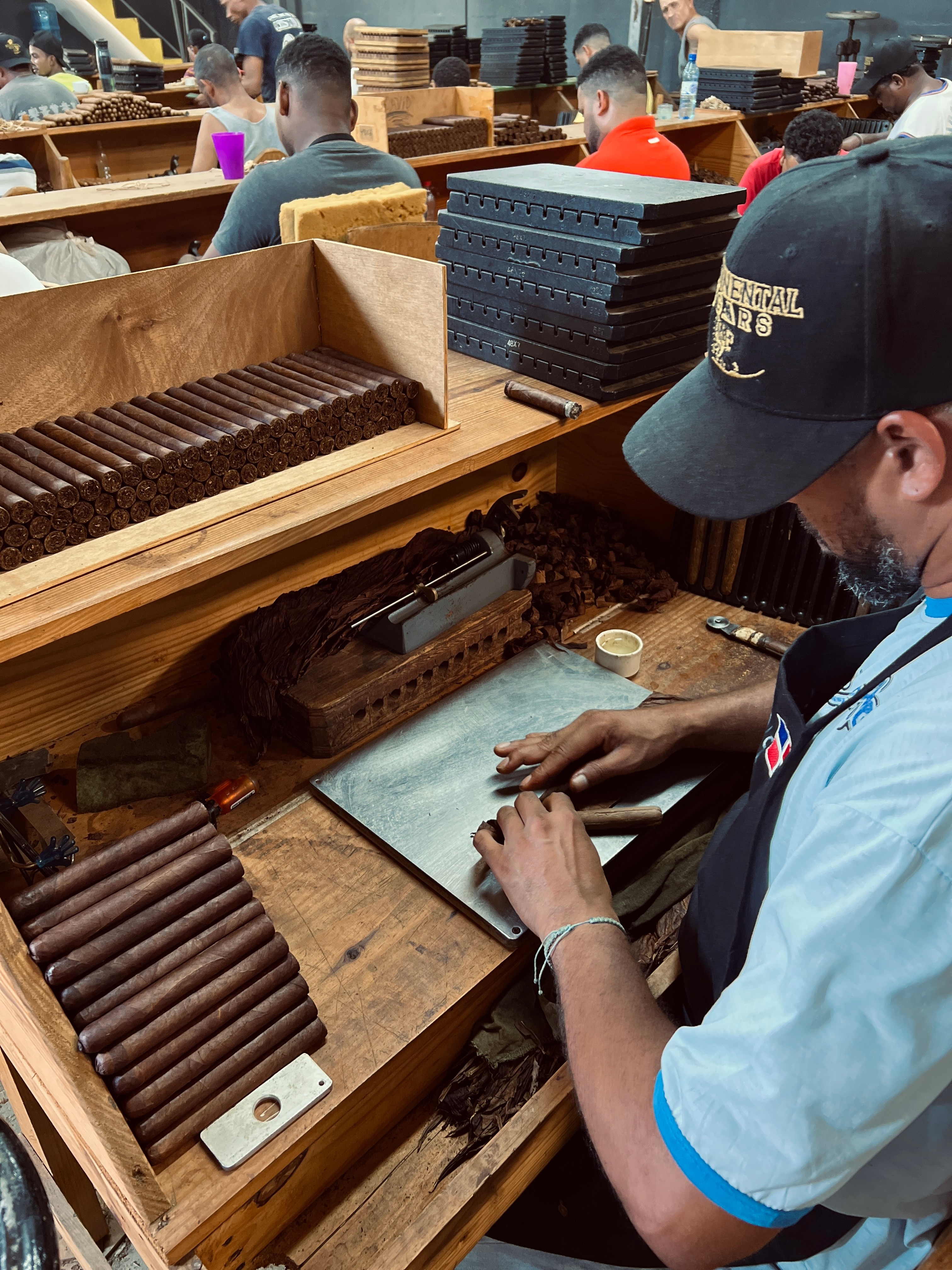 Person working with chocolate bars at a confectionery shop, surrounded by stacked chocolate products and equipment.