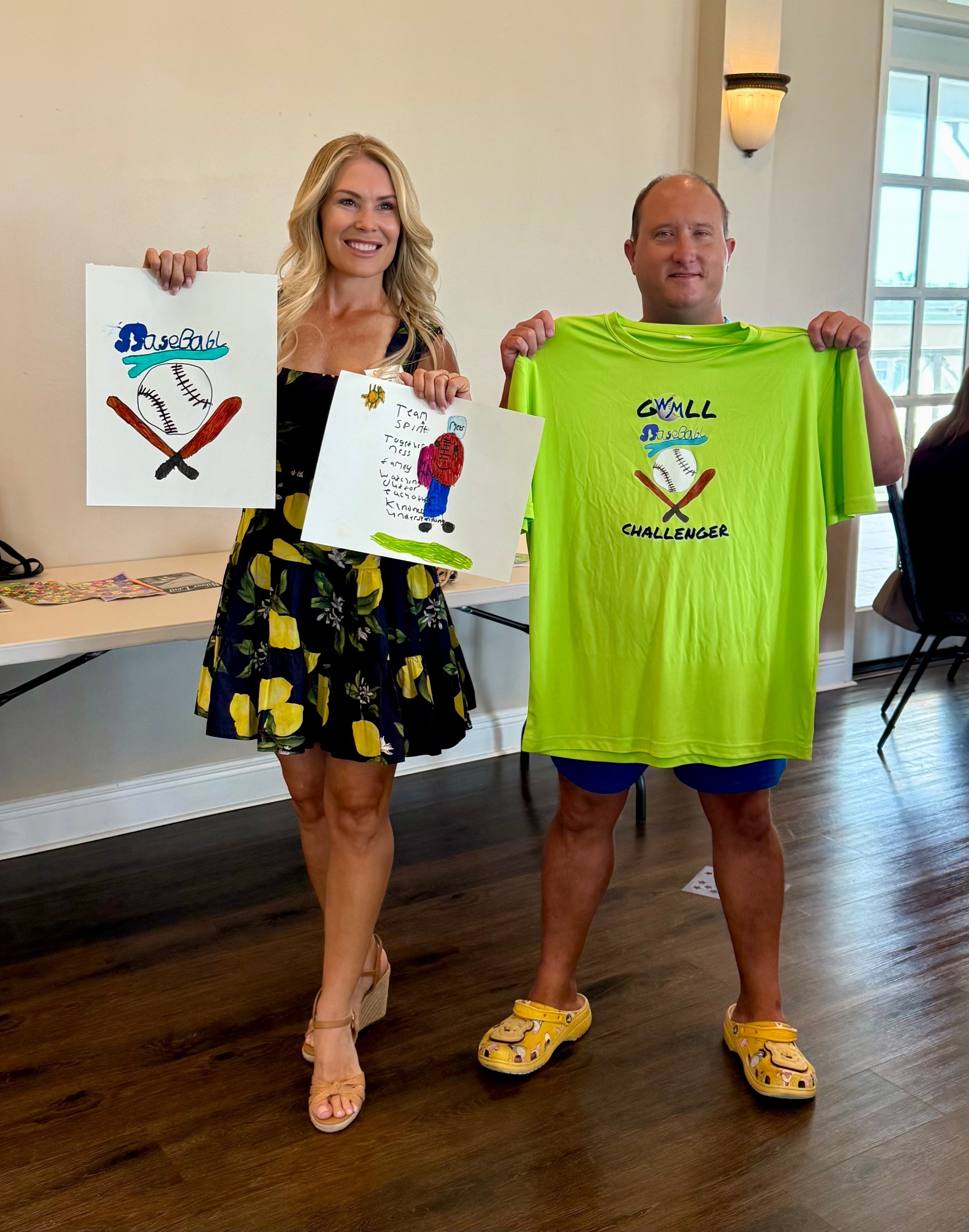 Woman and man holding signs and a bright green shirt indoors, smiling, with large windows in the background.